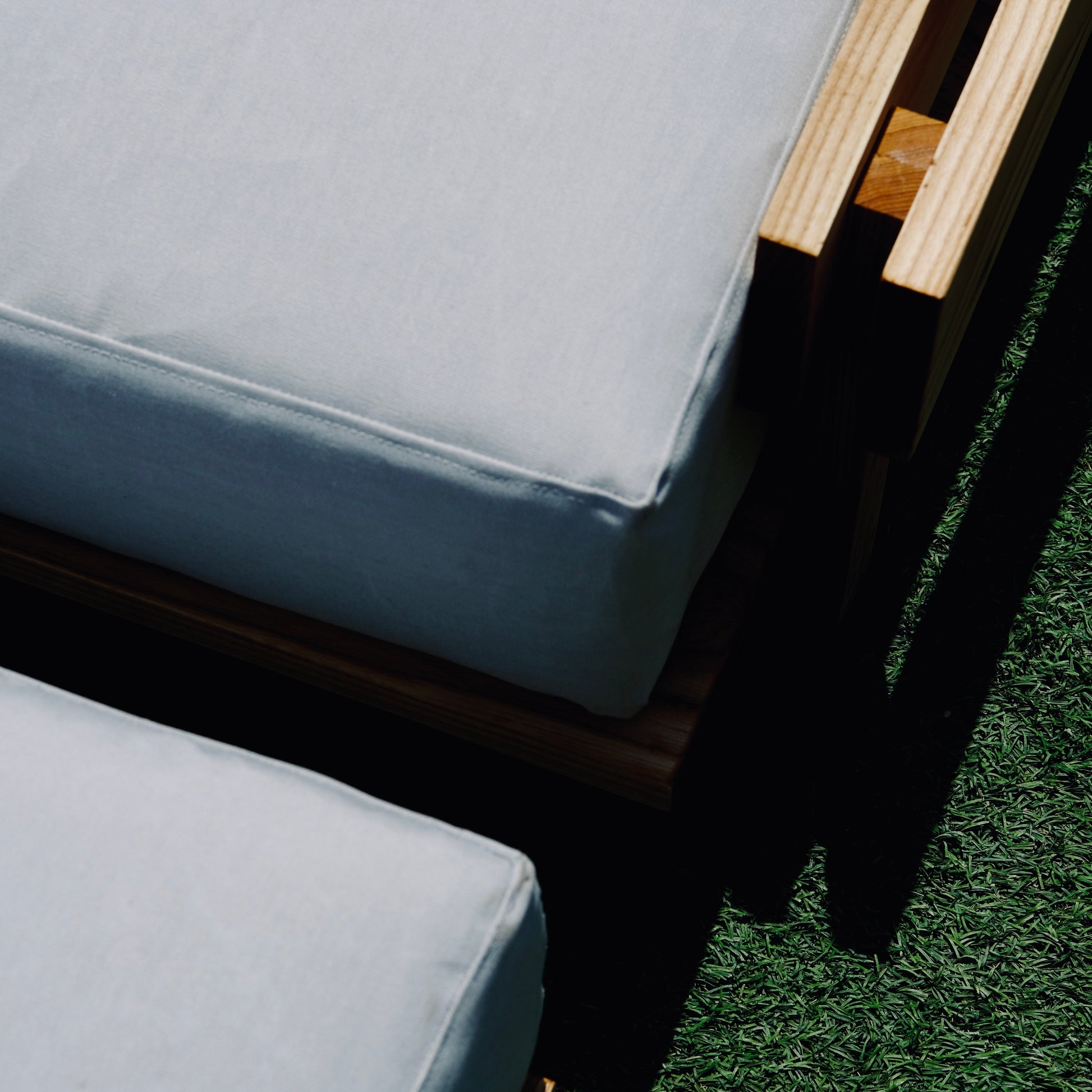 Close-up of outdoor furniture with cushions on a grassy surface