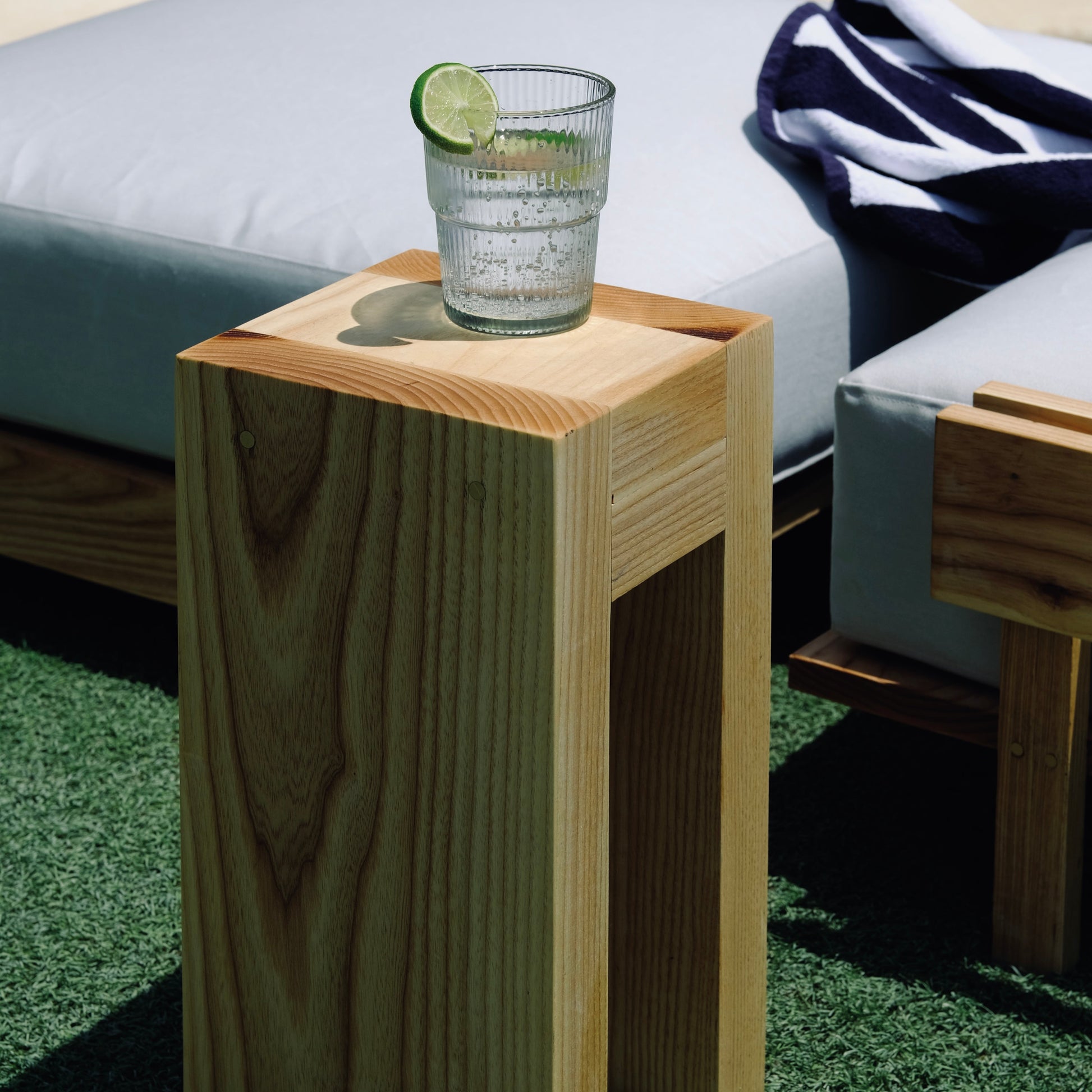 Wooden side table with a glass of water and lime on grass