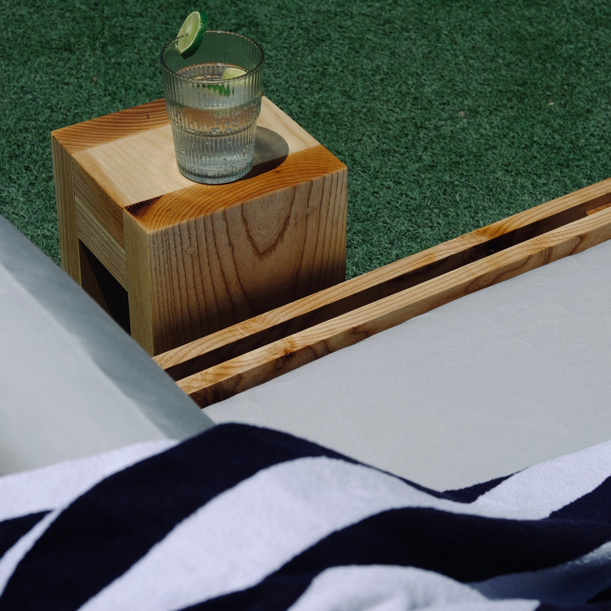 Glass of water on a wooden tray with a striped towel in the foreground