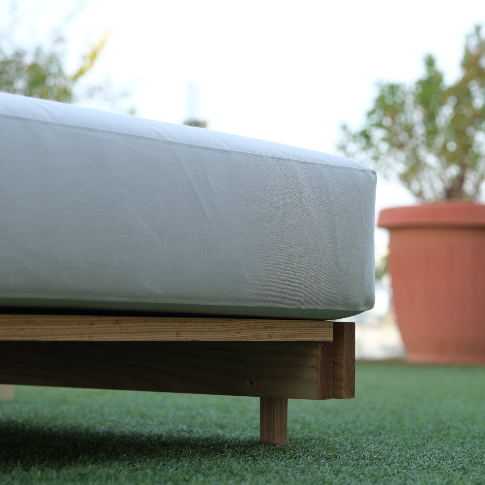 Close-up of wooden ottoman on a green wall with blurred background