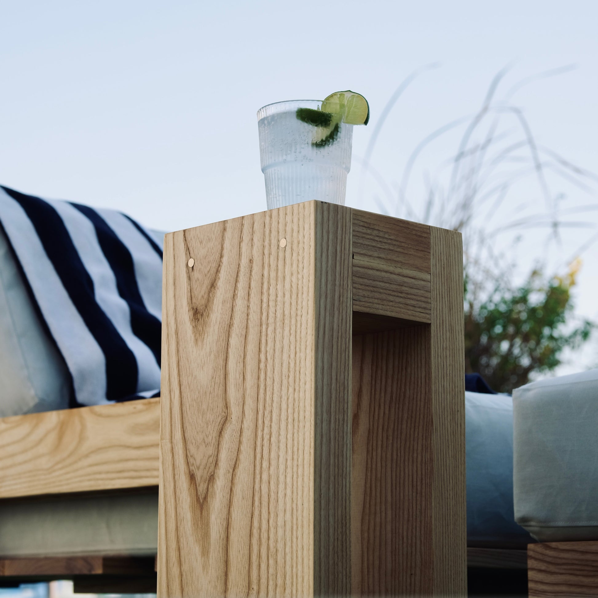 Glass of water with a lime wedge on a wooden table outdoors