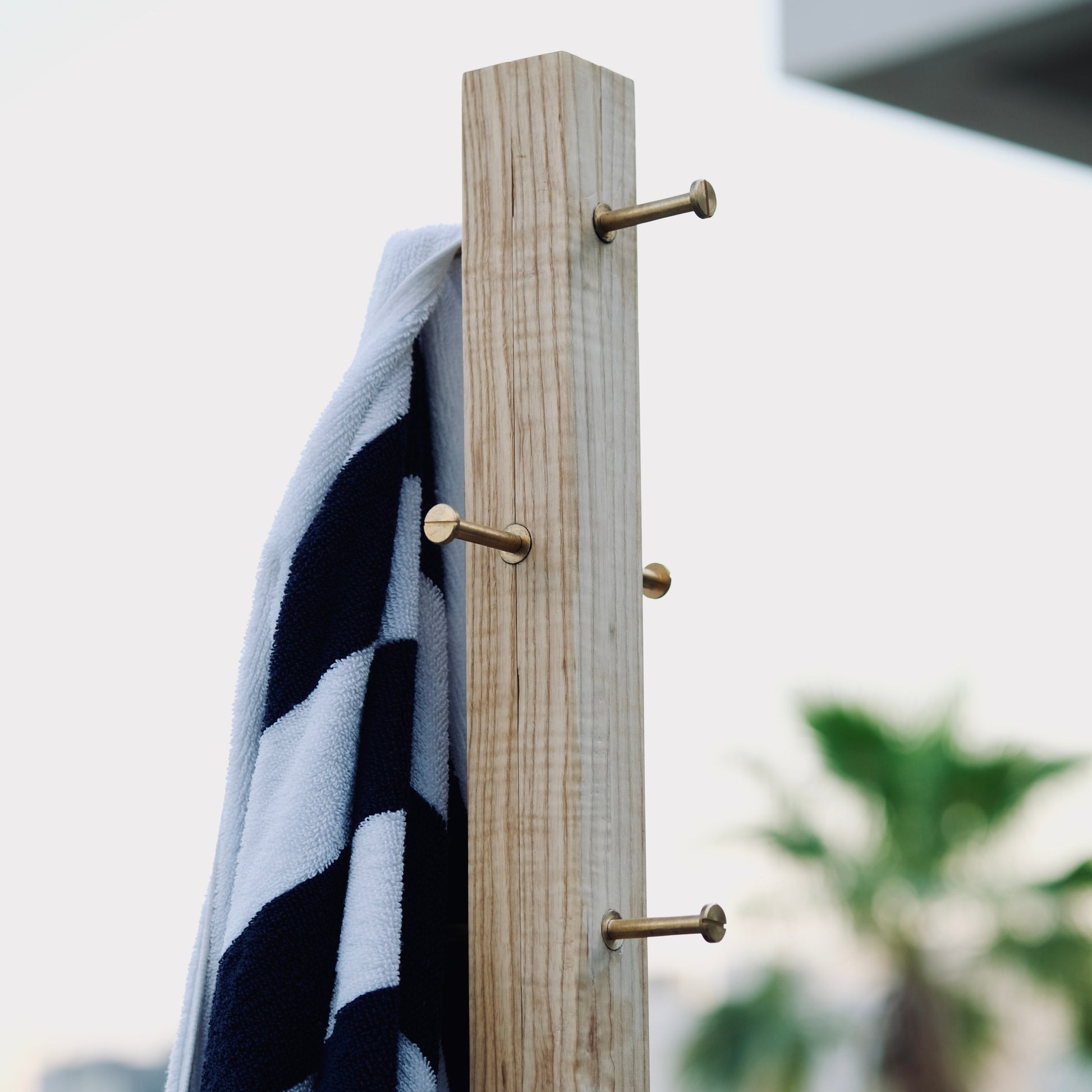 Black and white striped towel hanging on a wooden rack with blurred outdoor background
