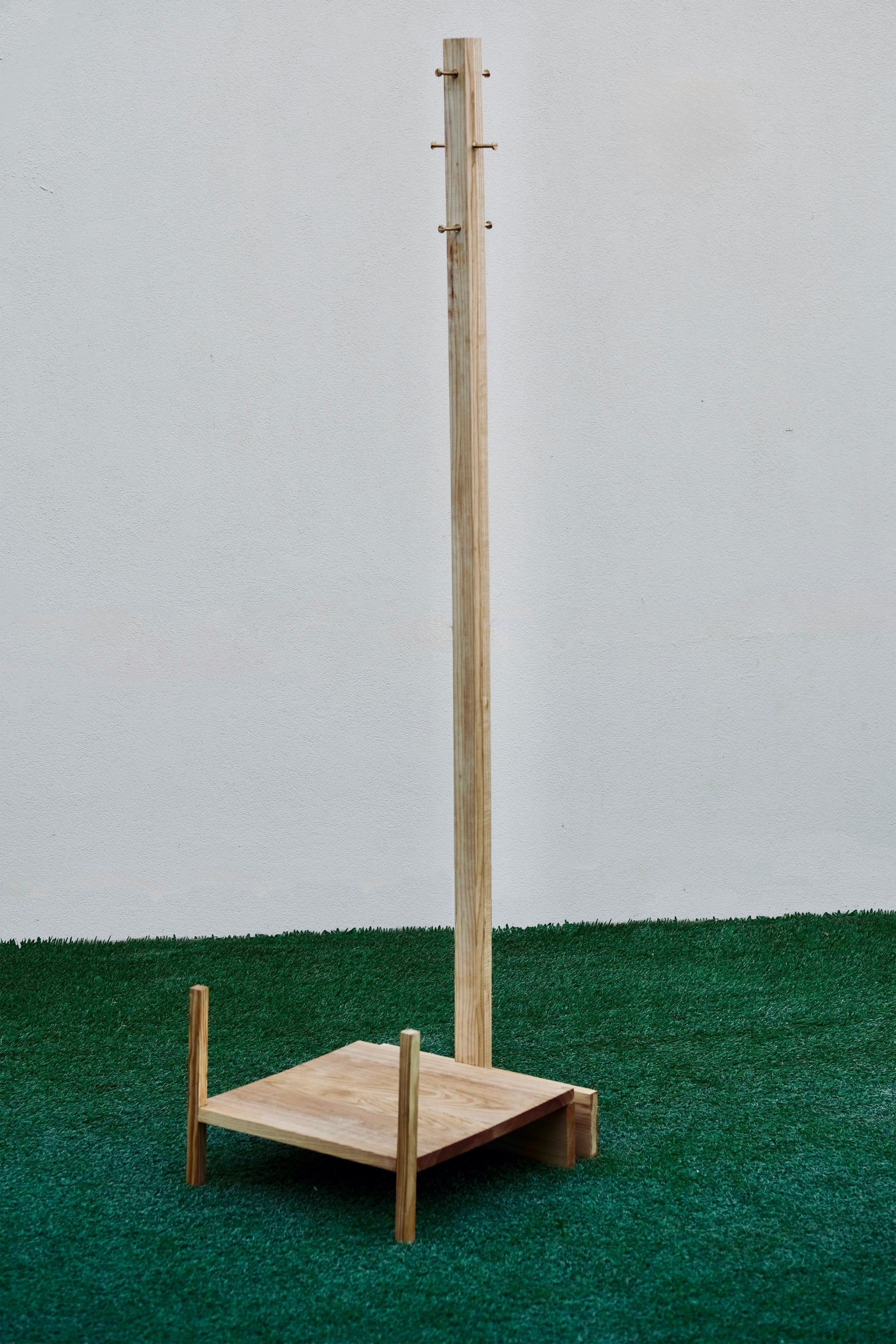 Wooden coat rack on a green surface with a white background